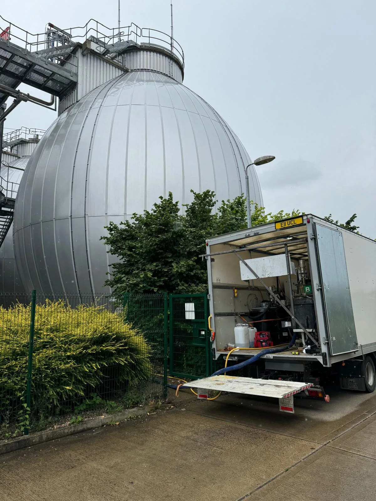 Exterior view of egg-shaped anaerobic gas digesters with a UCL Ltd service vehicle on site