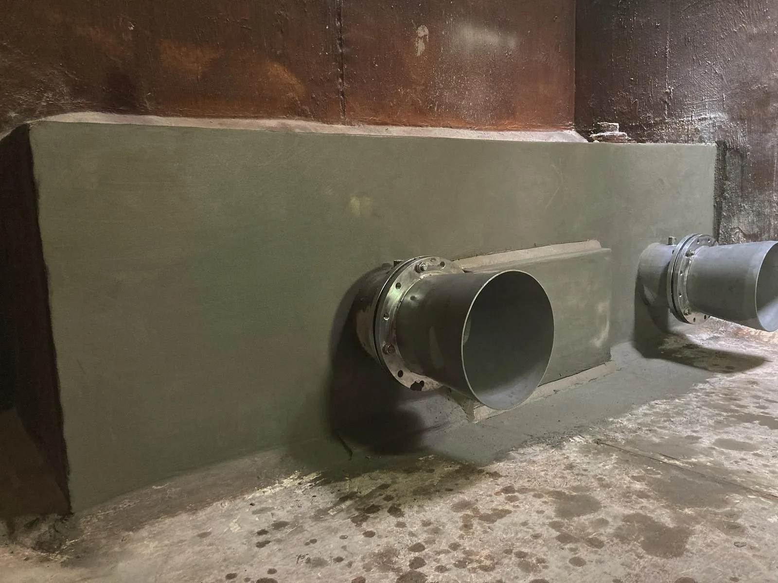 Repaired inlet pipe penetrations sealed with cementitious compound on a balance tank wall