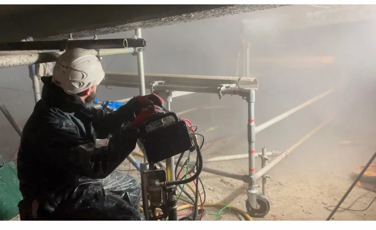 Engineer operating remote robotic ultra-high-pressure water jetting equipment inside a confined digester space