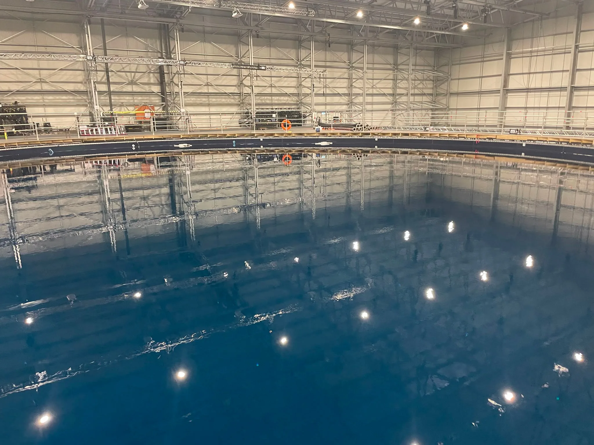 Wide interior view of a large underwater film production tank inside a studio soundstage